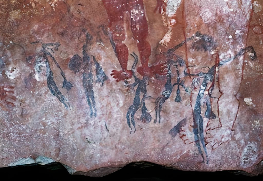 Bent Knee Figures wearing long conical headdresses and carrying boomerangs and feather bunches.